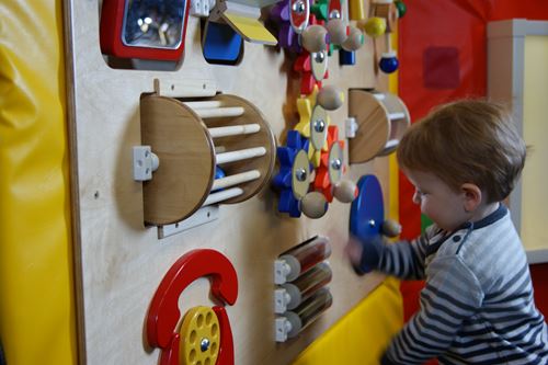 small child playing knobs and dials on a sensory wall